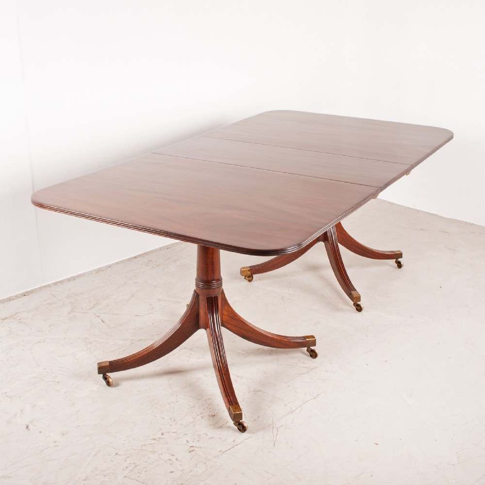 A mahogany twin pillar extending dining table featuring rounded table corners, reeded sabre legs, and brass castors. View VII