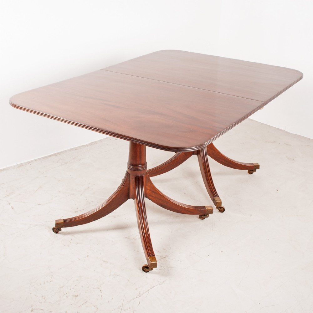 A mahogany twin pillar extending dining table featuring rounded table corners, reeded sabre legs, and brass castors. View VIII