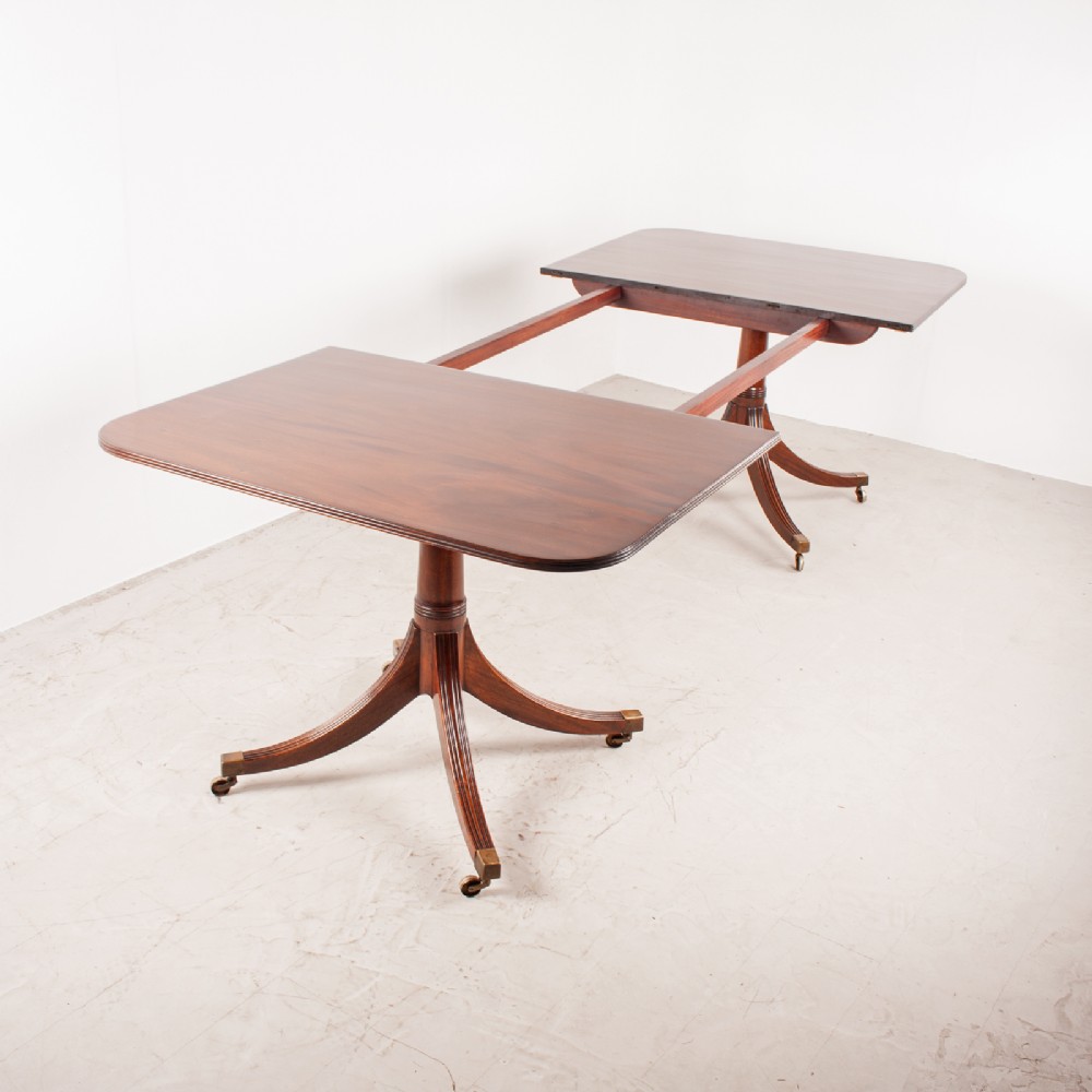 A mahogany twin pillar extending dining table featuring rounded table corners, reeded sabre legs, and brass castors. View IX