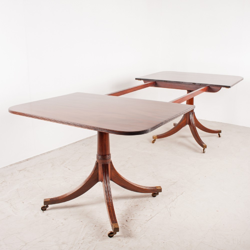 A mahogany twin pillar extending dining table featuring rounded table corners, reeded sabre legs, and brass castors. View X
