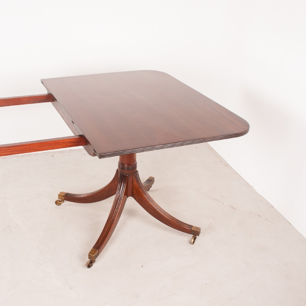 A mahogany twin pillar extending dining table featuring rounded table corners, reeded sabre legs, and brass castors. View XI