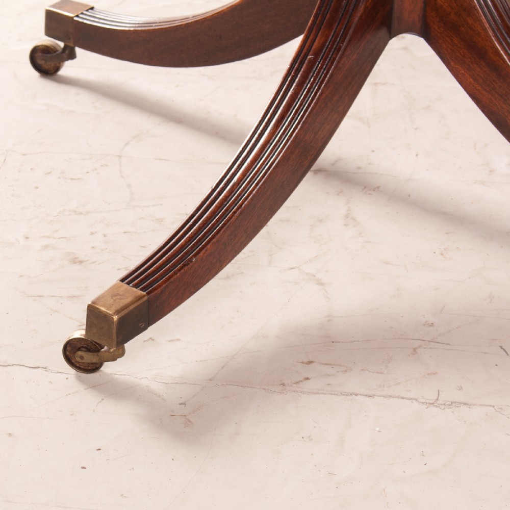 A mahogany twin pillar extending dining table featuring rounded table corners, reeded sabre legs, and brass castors. View XII