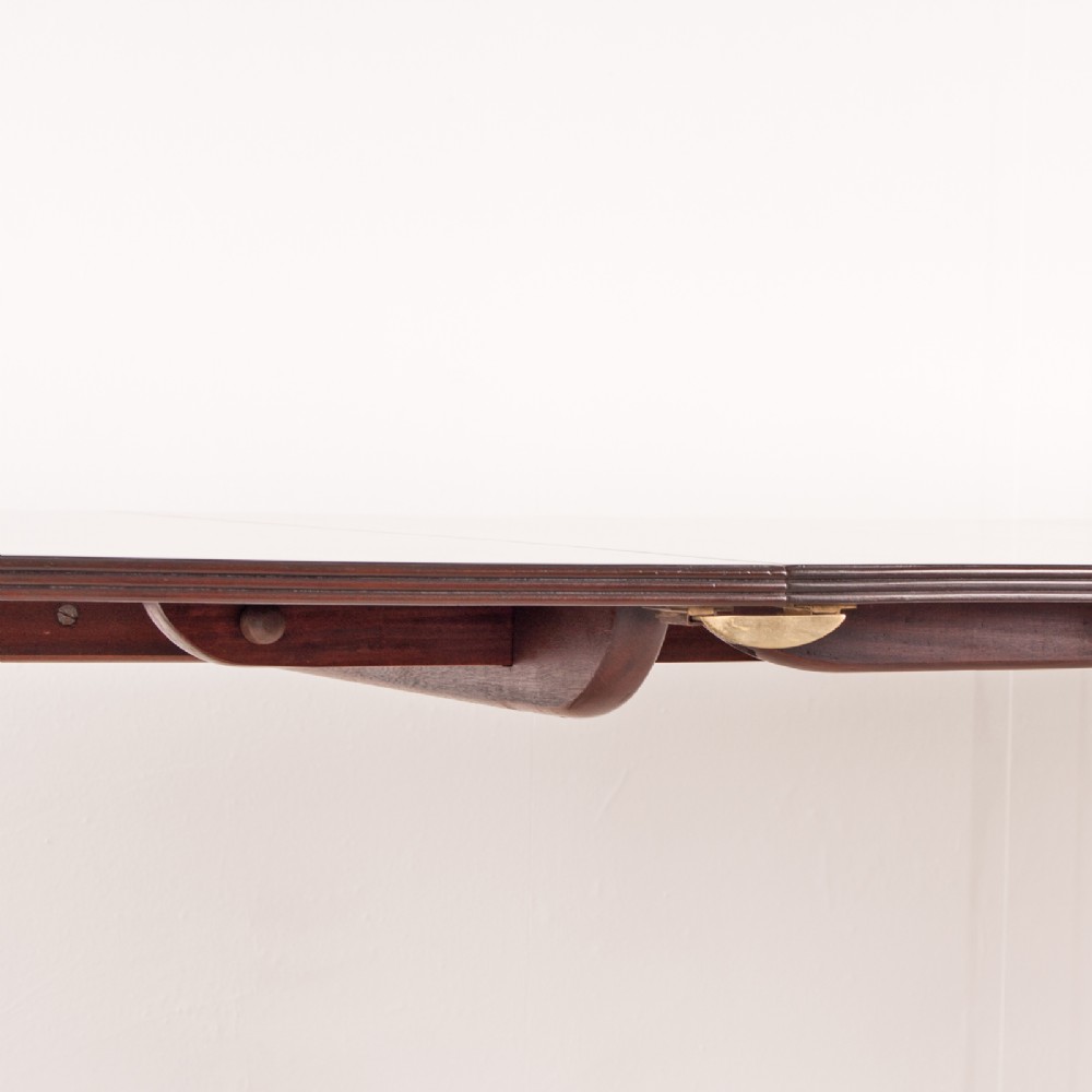 A mahogany twin pillar extending dining table featuring rounded table corners, reeded sabre legs, and brass castors. View XIII