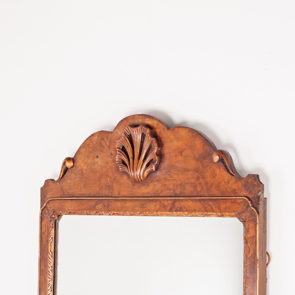 A rectangular walnut wall mirror with a contoured pediment top featuring a hand-carved shell motif. View VI