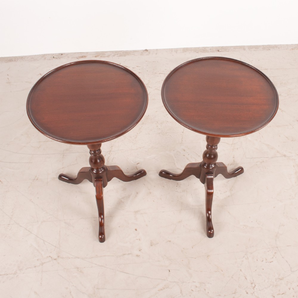 A matching pair of dark mahogany wine tables featuring dished circular tops, turned central pedestals, and splayed tripod legs. View III