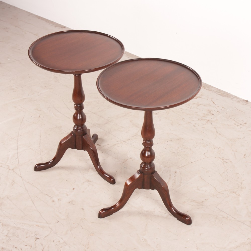 A matching pair of dark mahogany wine tables featuring dished circular tops, turned central pedestals, and splayed tripod legs. View VI