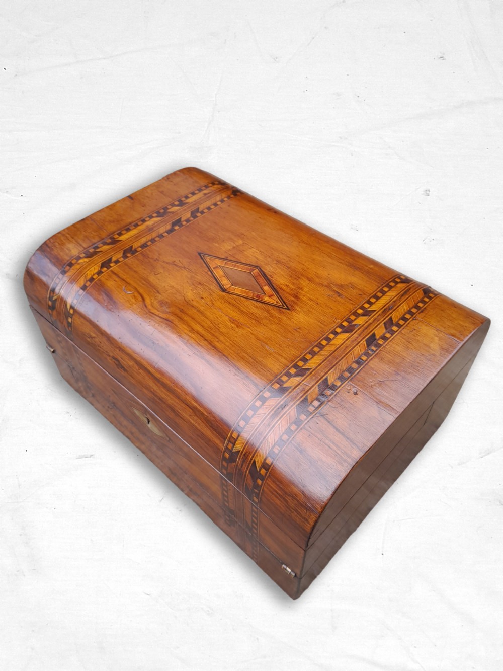 An antique walnut domed-top writing box with geometric parquetry inlay bands and a central diamond motif.