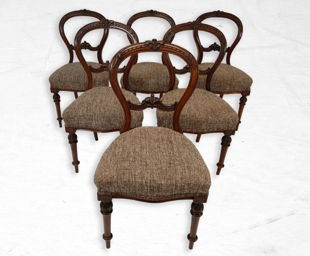 A set of six Victorian walnut balloon back dining chairs featuring carved backrest details, turned front legs, and textured brown upholstered seats.