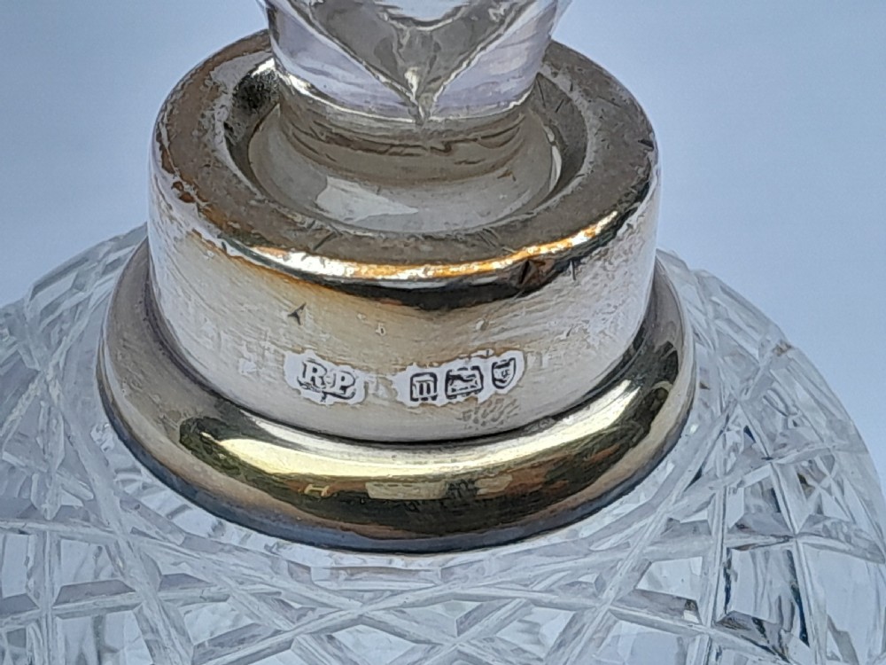 A cylindrical cut glass scent bottle featuring a hallmarked sterling silver collar and a faceted round glass stopper. View II