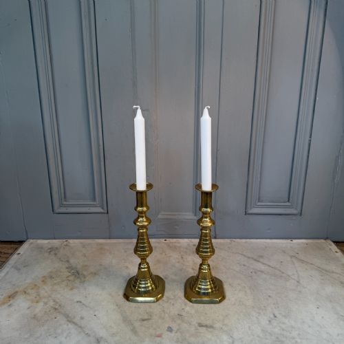 fig 1. A pair of Victorian brass candlesticks featuring turned beehive columns on stepped square bases, displayed with white taper candles.