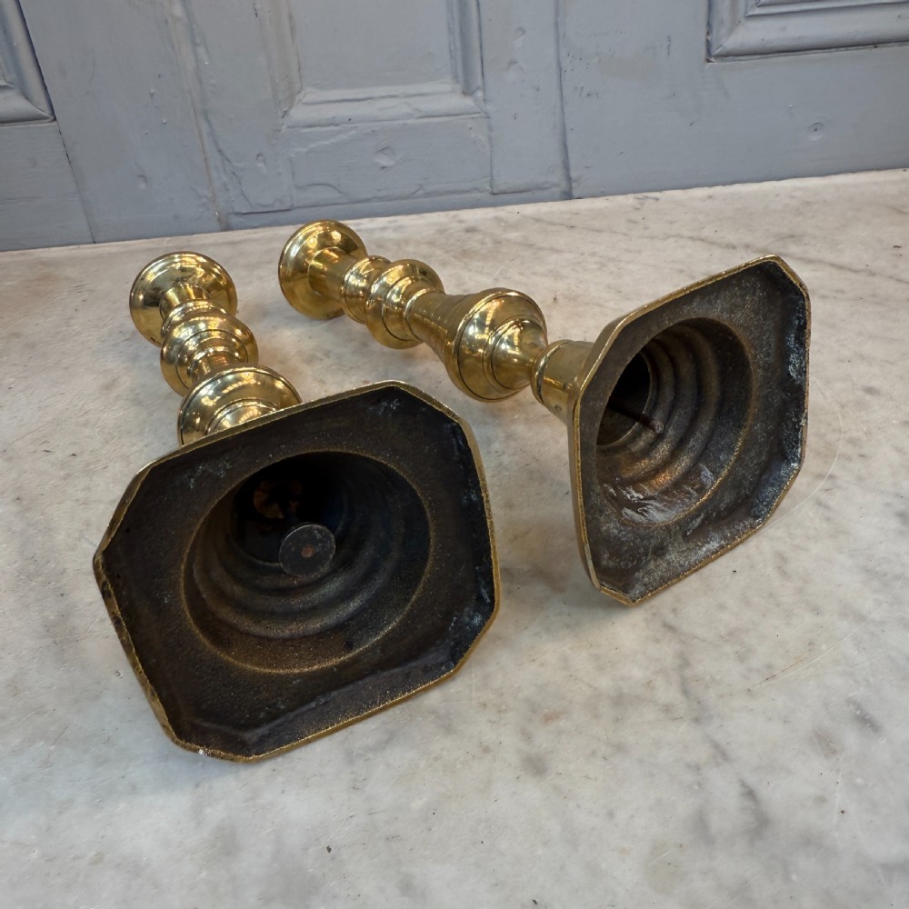 A pair of Victorian brass candlesticks featuring turned beehive columns on stepped square bases, displayed with white taper candles. View VIII