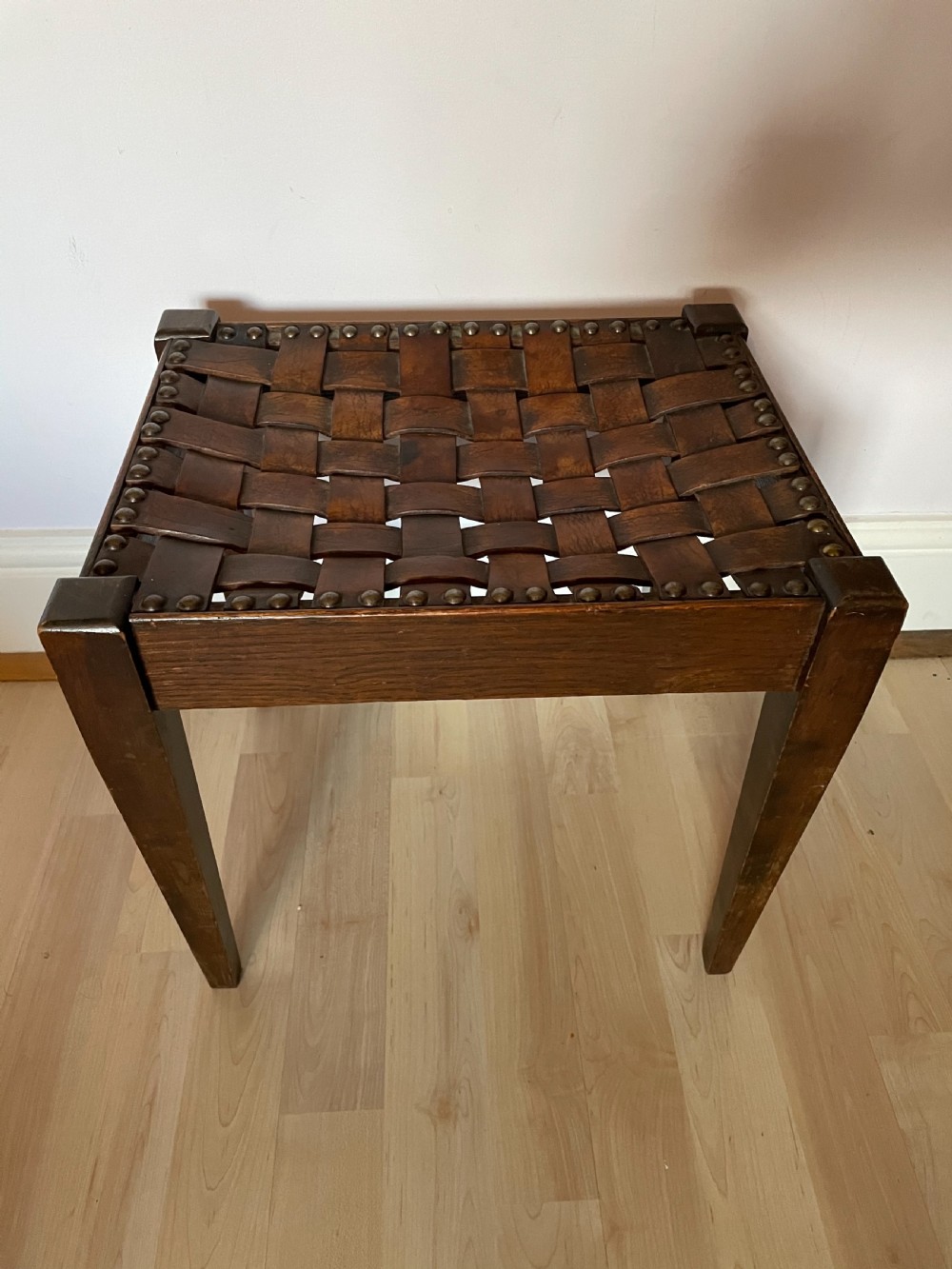 An Arts and Crafts oak and leather stool, attributed to Arthur Simpson