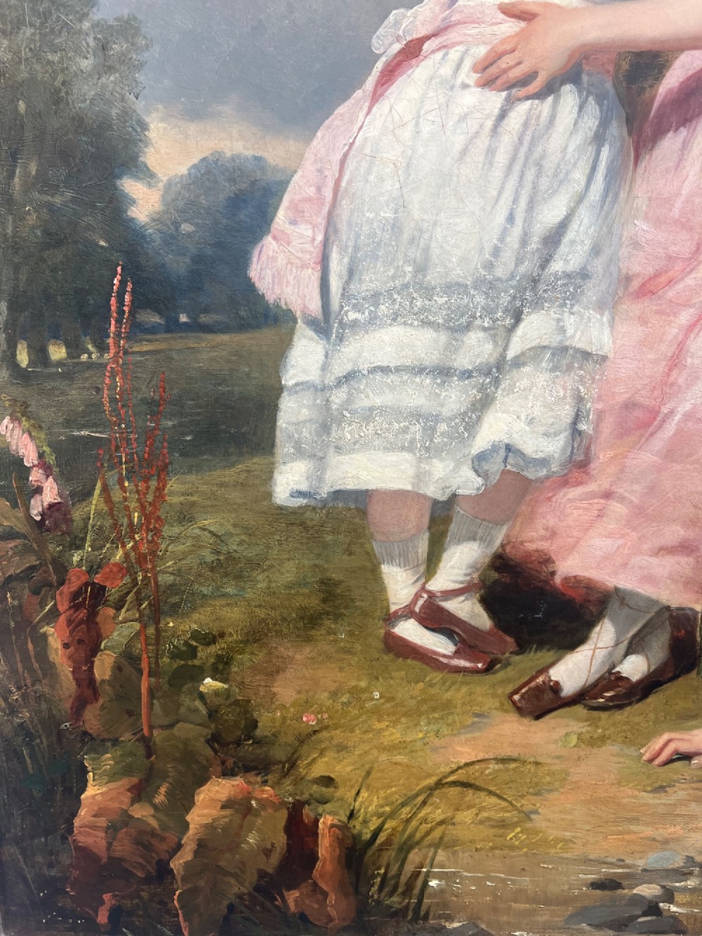 An antique oil painting depicting three young children posed outdoors near a large tree within a molded wooden frame. View III