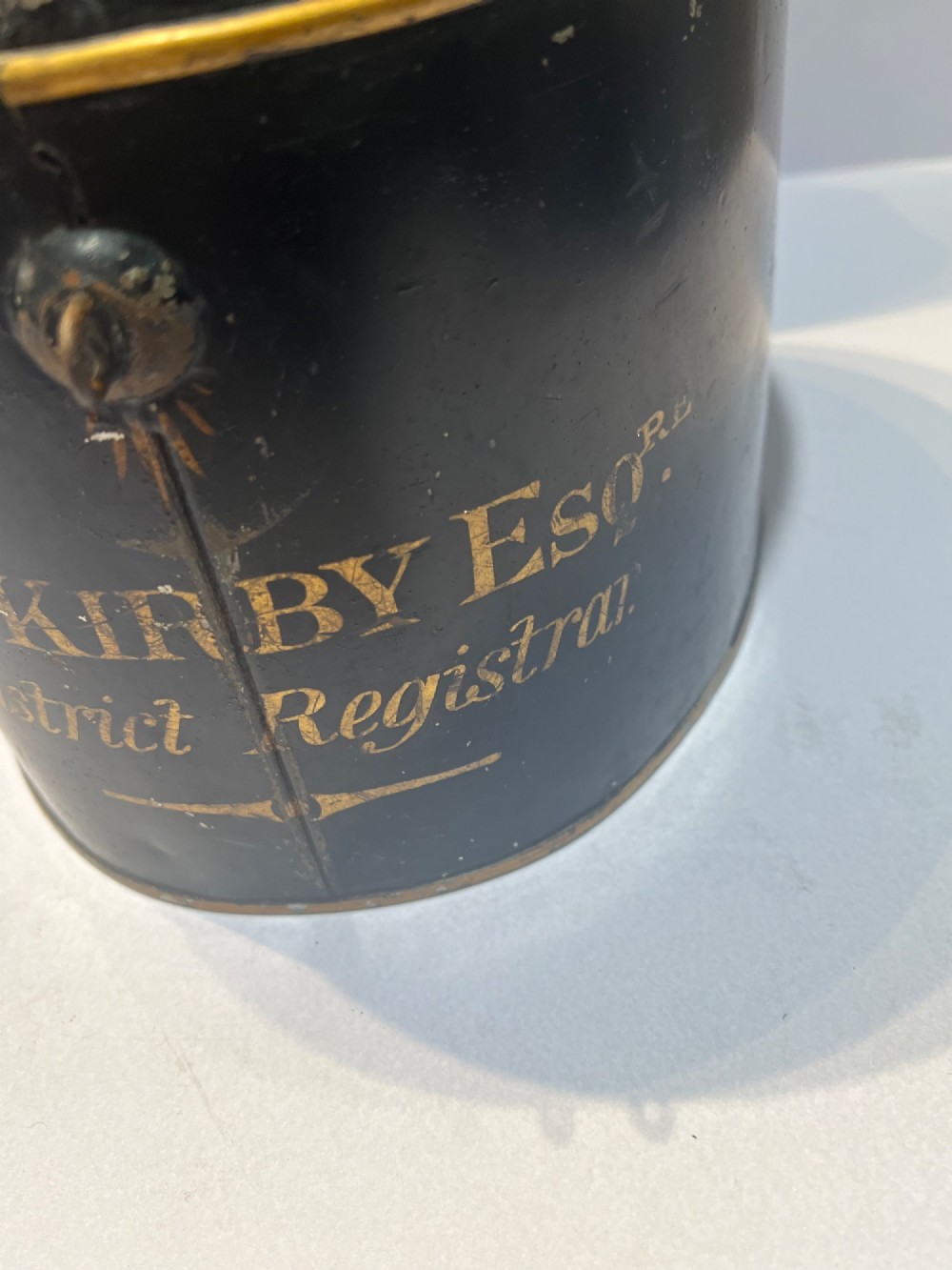 An antique horsehair barrister wig displayed on an internal wire stand next to a black painted metal tin case featuring gold lettering. View IX