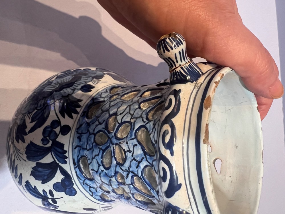 An 18th-century Dutch Delft tin-glazed earthenware puzzle jug featuring hand-painted blue floral motifs, a reticulated neck, and circular spouts along the upper rim. View V