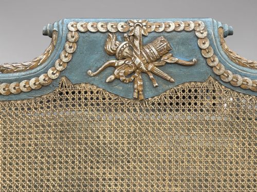 fig 3. A late 19th-century Louis XVI style settee featuring blue painted trim with gold leaf details, woven cane seat and back panels, and six fluted legs.