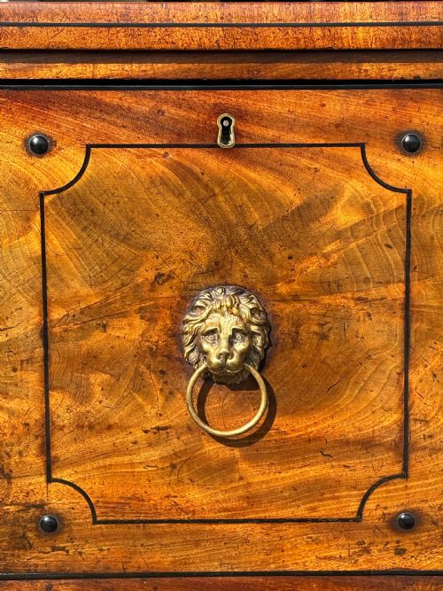 fig 2. A 19th-century George IV flame mahogany breakfront sideboard featuring ebony stringing, lion-mask brass handles, spiral pilasters, and fluted legs.