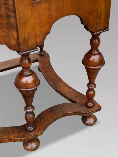 fig 3. An 18th-century Queen Anne walnut chest on stand featuring figured veneers, brass drop handles, a shaped lower apron, and turned legs joined by stretchers.