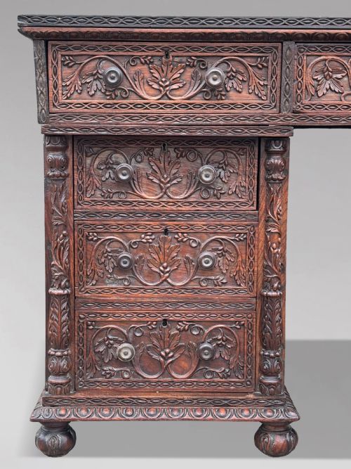 fig 3. Nineteenth-century Anglo-Indian carved padauk partners desk featuring intricate foliate relief carvings across the pedestal drawers and side panels on turned bun feet.