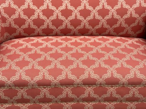 fig 2. A 19th-century Victorian upholstered sofa featuring terracotta and cream patterned fabric, rolled arms, and dark turned wooden legs on brass castors.