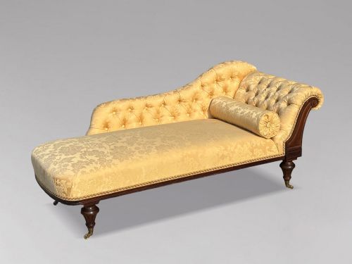 fig 2. A 19th-century Regency mahogany chaise longue upholstered in yellow damask fabric with deep buttoning, a bolster cushion, and turned legs on brass castors.