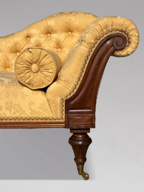 fig 3. A 19th-century Regency mahogany chaise longue upholstered in yellow damask fabric with deep buttoning, a bolster cushion, and turned legs on brass castors.