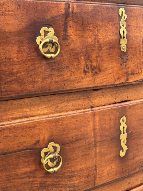 fig 2. A 17th-century French Provincial walnut commode featuring three long drawers decorated with brass drop handles and central escutcheons.