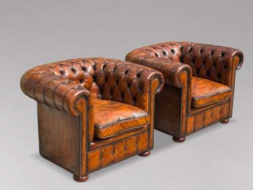 fig 1. A pair of late Victorian deep-buttoned brown leather Chesterfield club armchairs with rolled arms, brass studding, and turned wooden feet.