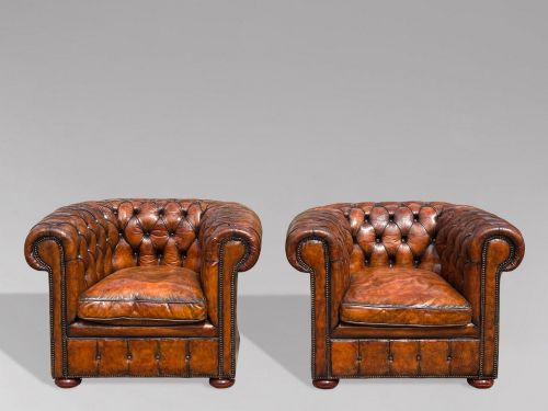 fig 2. A pair of late Victorian deep-buttoned brown leather Chesterfield club armchairs with rolled arms, brass studding, and turned wooden feet.