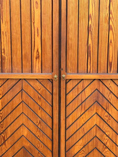 fig 3. A late 19th-century pitch pine Arts and Crafts wardrobe featuring vertical slatted upper door panels, chevron lower panels, and a carved cresting rail.