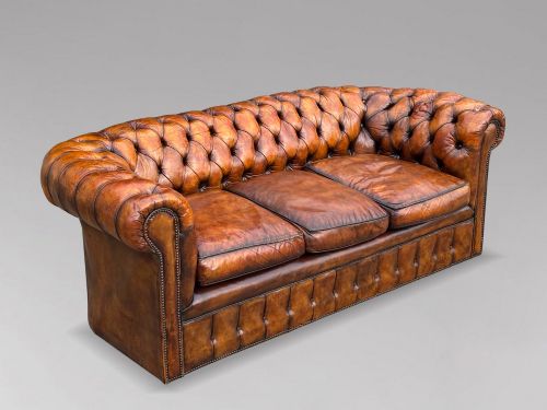 fig 1. A nineteenth-century Victorian three-seater Chesterfield sofa upholstered in aged warm brown leather with deep button tufting and nailhead trim.
