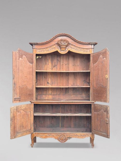 fig 3. An 18th-century French Louis XVI carved oak buffet deux corps featuring two upper panelled doors topped with a floral basket carving above a two-door base resting on short scrolled feet.