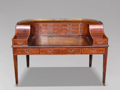 fig 2. An 18th-century George III mahogany Carlton House desk with inlaid marquetry, a leather writing surface, small upper drawers, and tapered legs on brass castors.