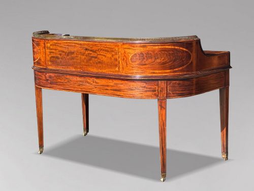 fig 3. An 18th-century George III mahogany Carlton House desk with inlaid marquetry, a leather writing surface, small upper drawers, and tapered legs on brass castors.