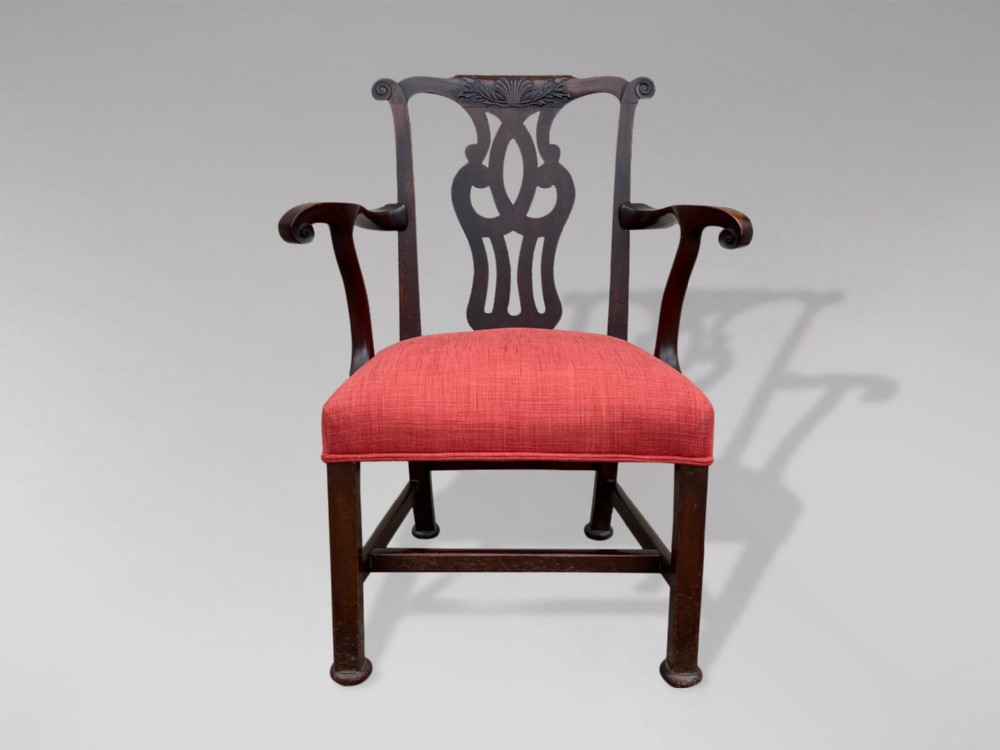 An 18th-century Georgian mahogany armchair featuring a pierced back splat, serpentine arms, and a red fabric upholstered seat.