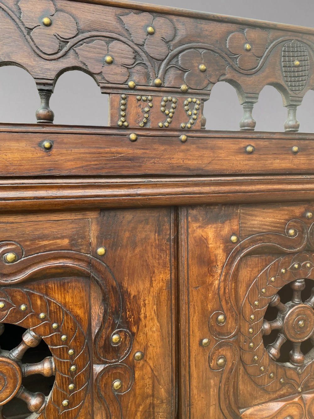 A 19th-century carved dark wood Breton cupboard featuring spindle turnings, openwork geometric wheel motifs, and a gallery top raised on tall straight legs with an under-shelf. View IV