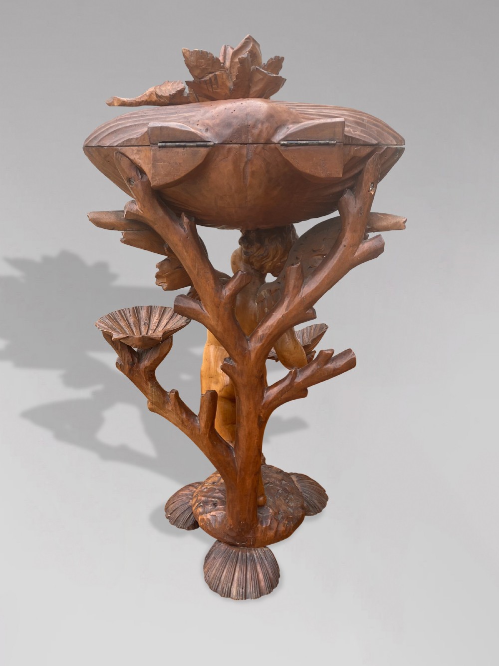 A 19th-century carved wooden figure of a winged putto holding a large scallop shell basin overhead while standing on a shell-shaped base. View VI