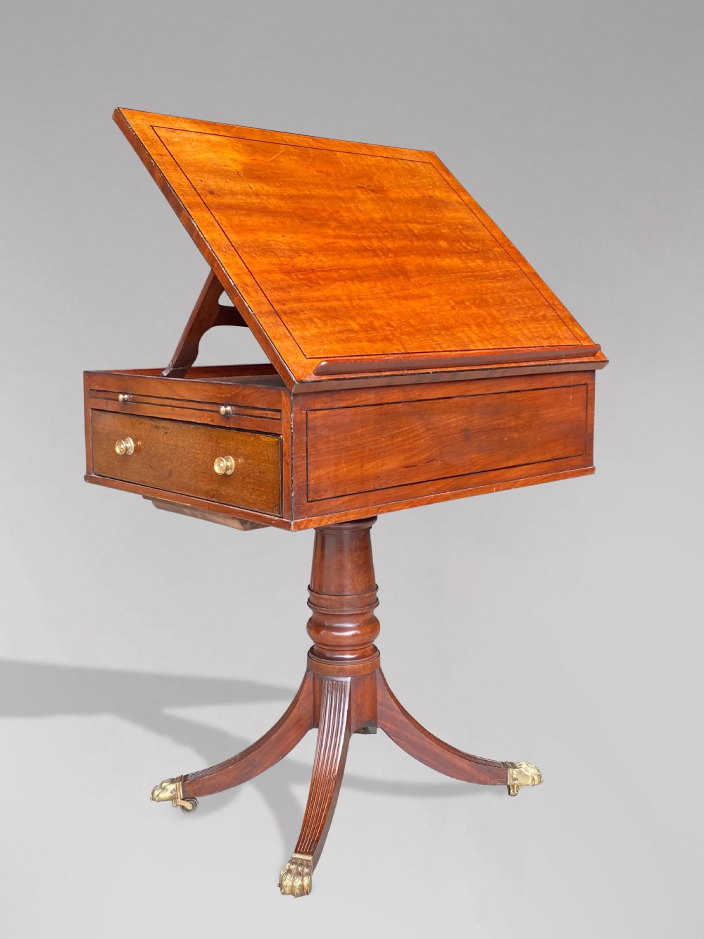 A George III mahogany reading table featuring an adjustable tilted top, a side drawer, a turned pedestal stem, and reeded tripod legs with brass paw feet. View II