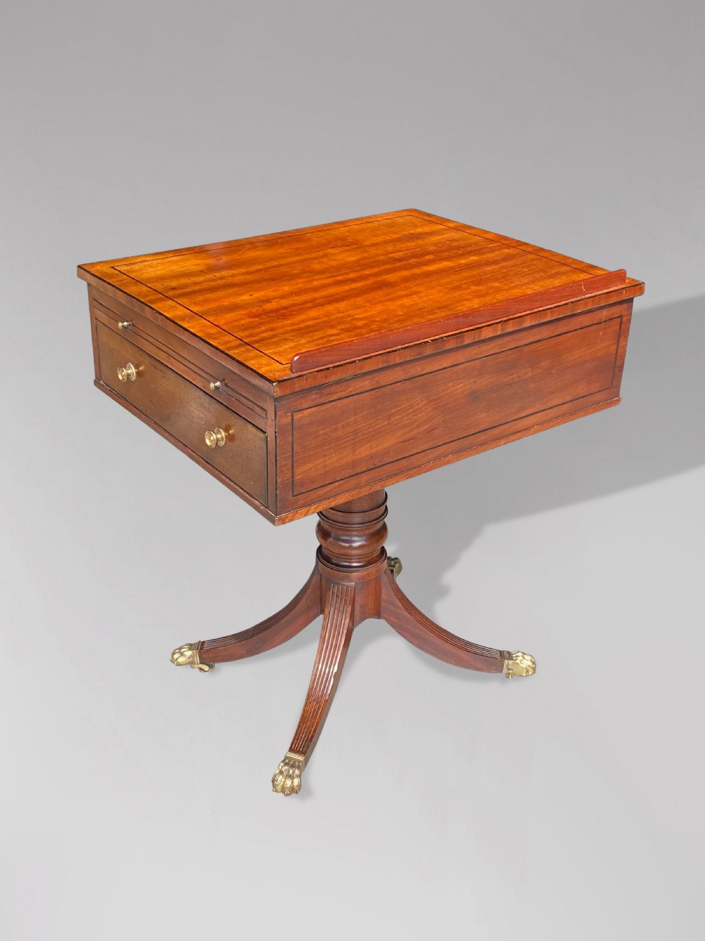 A George III mahogany reading table featuring an adjustable tilted top, a side drawer, a turned pedestal stem, and reeded tripod legs with brass paw feet. View III