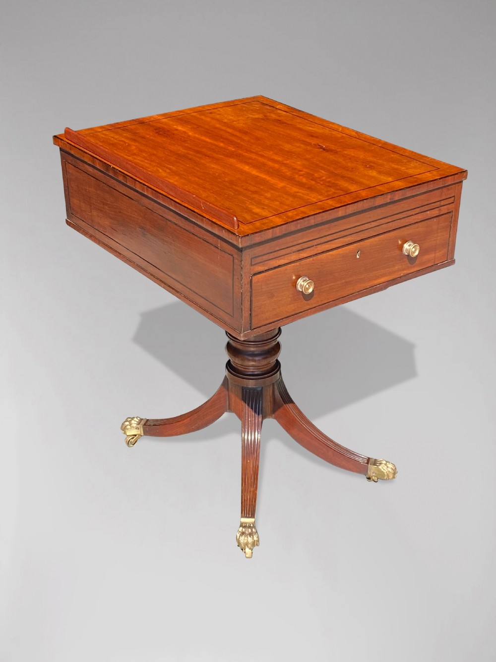 A George III mahogany reading table featuring an adjustable tilted top, a side drawer, a turned pedestal stem, and reeded tripod legs with brass paw feet. View V