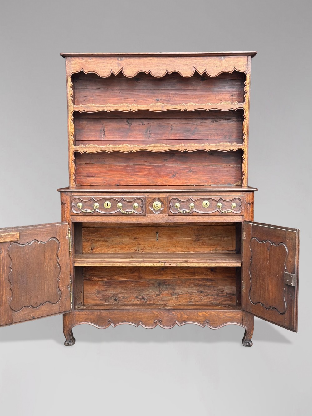 An 18th-century French provincial walnut buffet vaisselier featuring a two-door cabinet with carved panels and drawers beneath an open three-shelf plate rack with scalloped friezes. View II