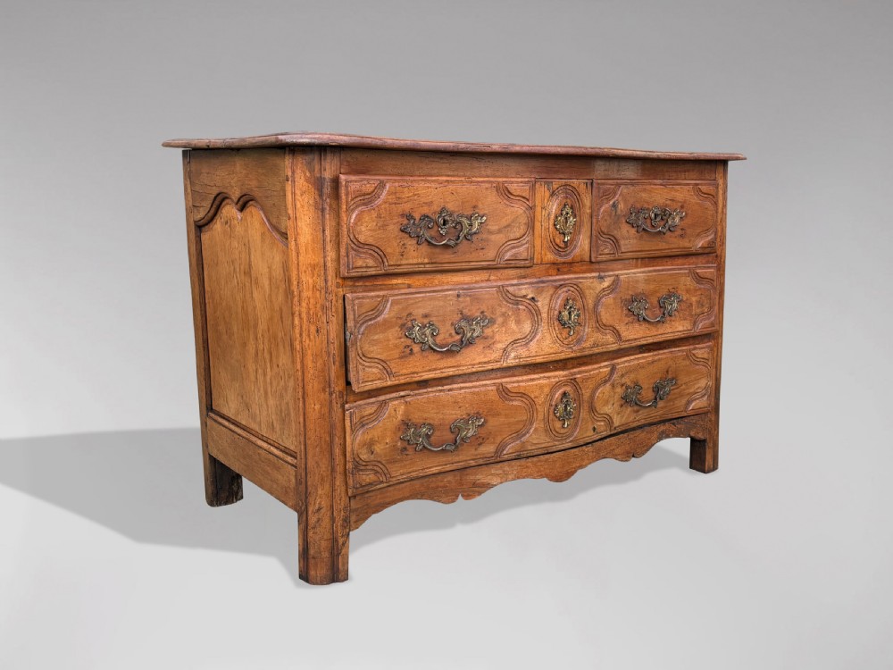 An 18th-century French Provincial walnut commode with three moulded drawers and decorative brass handles.