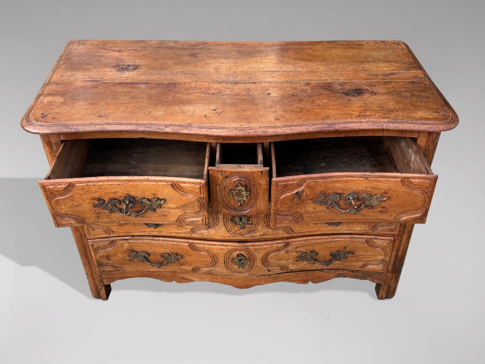 An 18th-century French Provincial walnut commode with three moulded drawers and decorative brass handles. View V