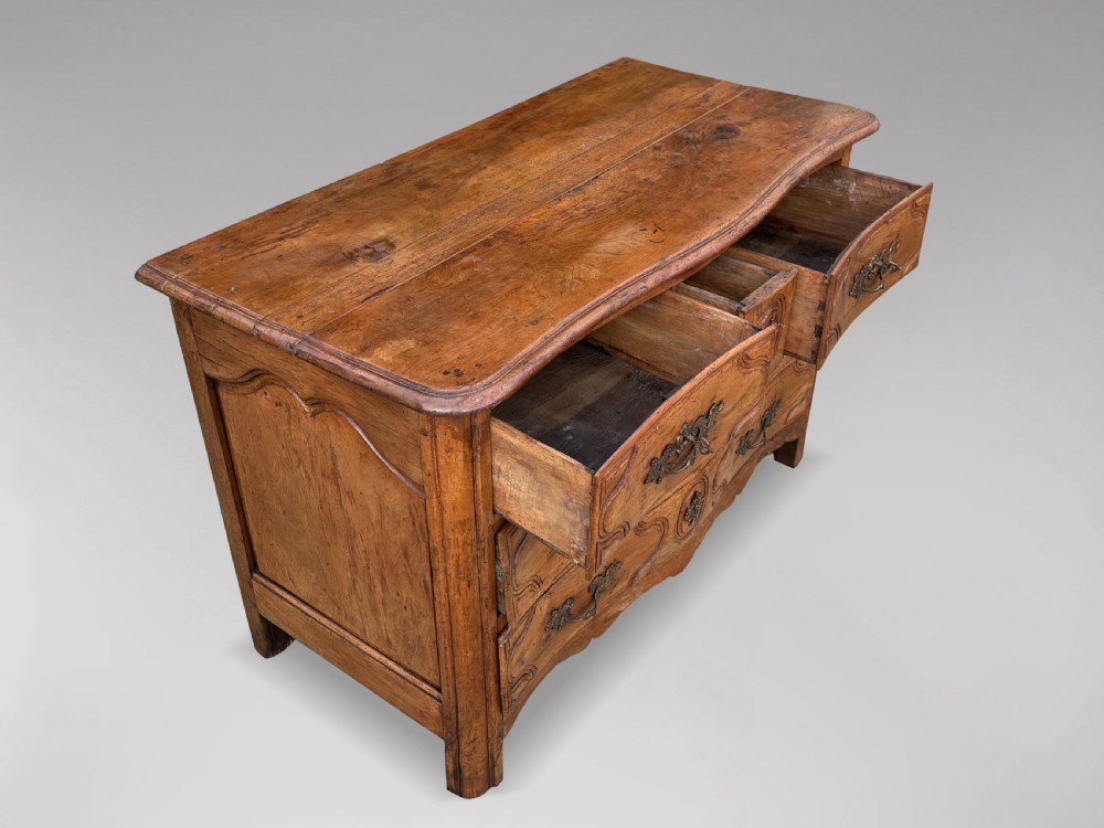 An 18th-century French Provincial walnut commode with three moulded drawers and decorative brass handles. View VI