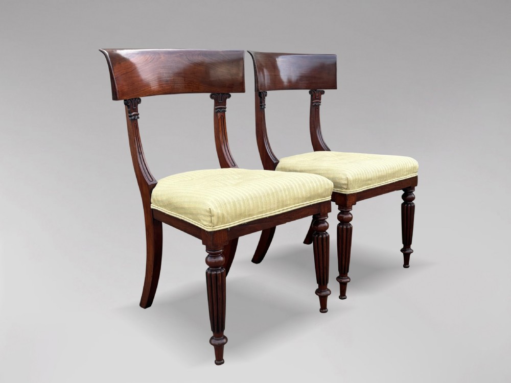 A pair of 19th-century William IV mahogany side chairs featuring curved top rails, fluted turned front legs, and pale yellow upholstered seats. View II