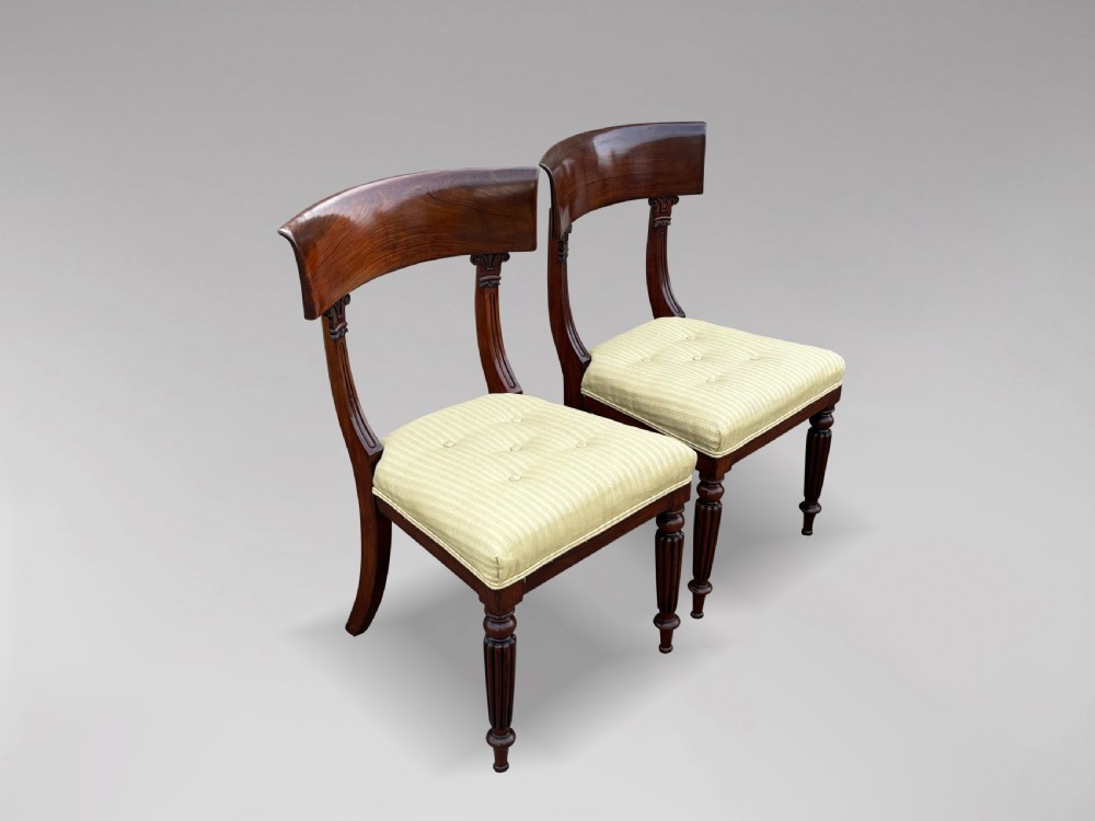 A pair of 19th-century William IV mahogany side chairs featuring curved top rails, fluted turned front legs, and pale yellow upholstered seats. View VI