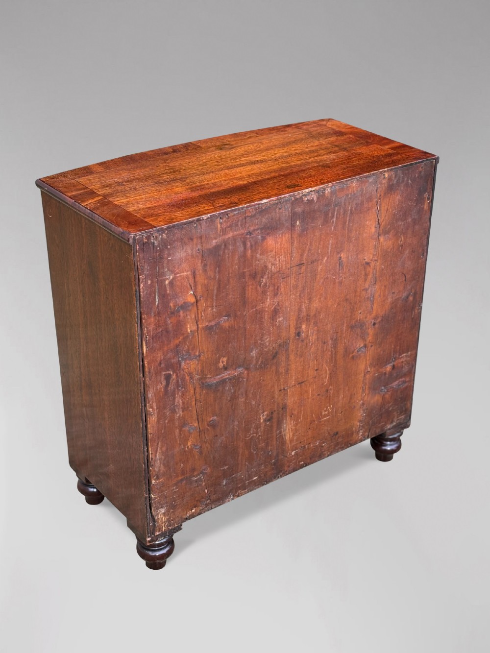 A nineteenth-century miniature mahogany bowfront chest of drawers featuring turned wooden knobs and bun feet. View IV