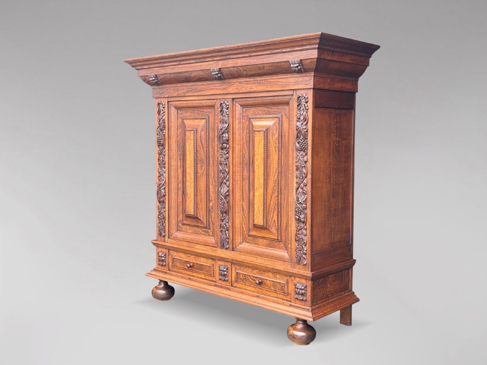 A 19th-century rosewood Renaissance Revival cabinet featuring relief foliage borders, fielded double doors, two lower drawers, and spherical bun feet.
