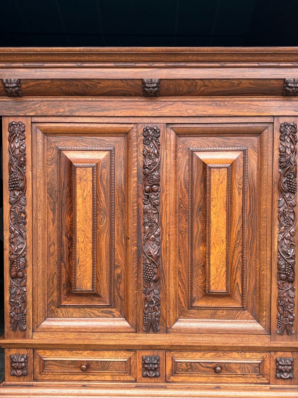 A 19th-century rosewood Renaissance Revival cabinet featuring relief foliage borders, fielded double doors, two lower drawers, and spherical bun feet. View VI