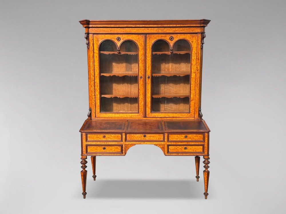A 19th-century French maple bureau bookcase featuring a top glazed two-door display section above a kneehole writing desk with leather inset panels and turned legs.